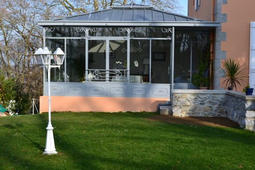véranda en acier toiture en panneaux isolants décorations en fer forgé